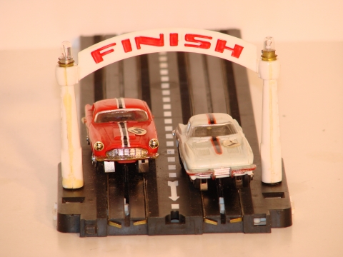 HO CARS GOING UNDER THE LIGHTED FINISH BANNER